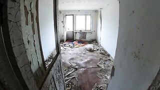 A chick is walking around horrible buildings, and suddenly she kneels down