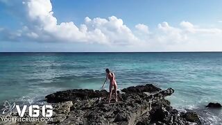 A pretty woman sunbathes naked on the beach, showcasing her petite frame