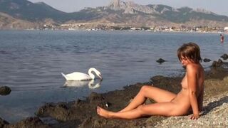 A hot naked girl is walking along the riverbank