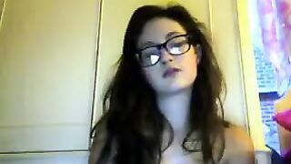 A cute girl in glasses removes her clothes during a video call