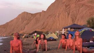 A group of young people are playing volleyball naked on the beach